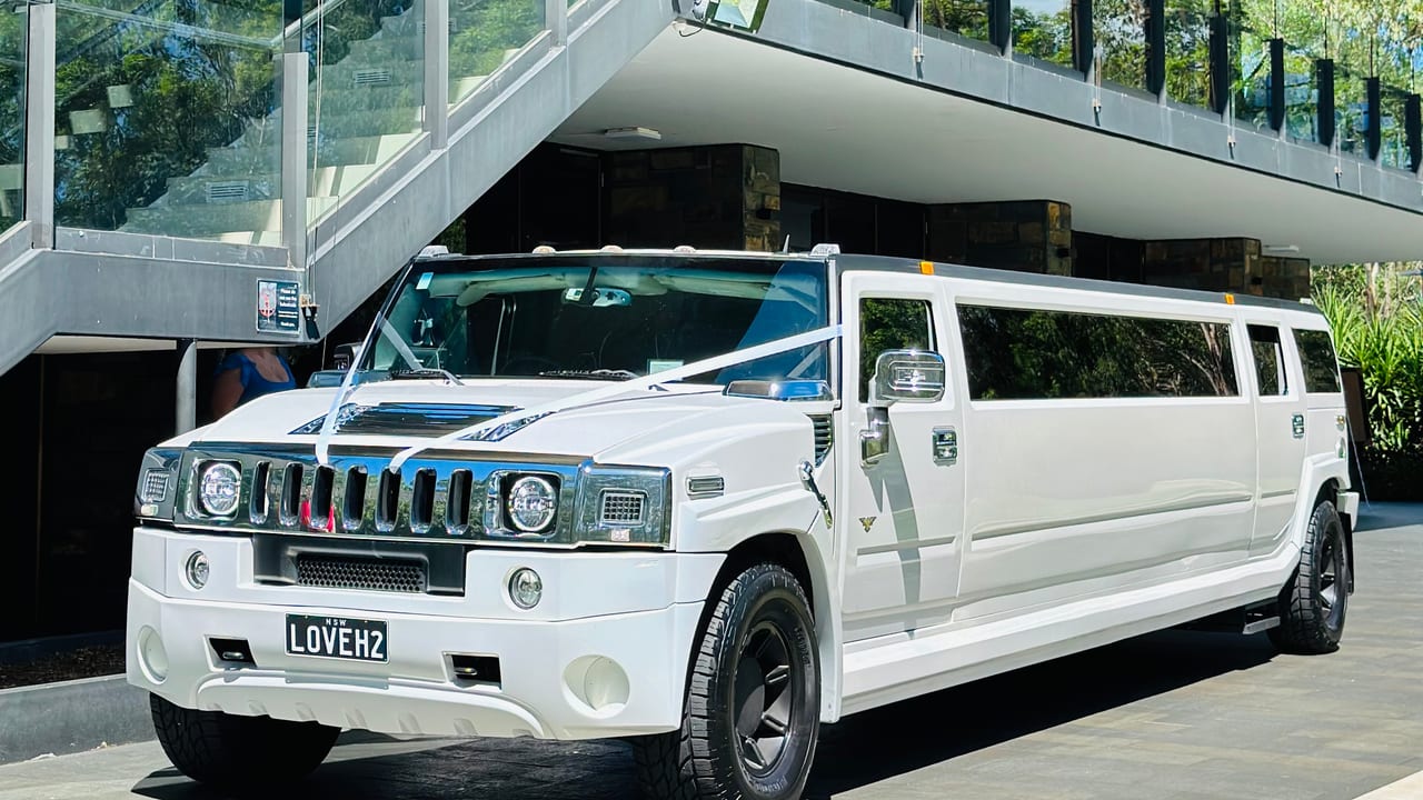 White H2 stretch Hummer limousine outside a glass building