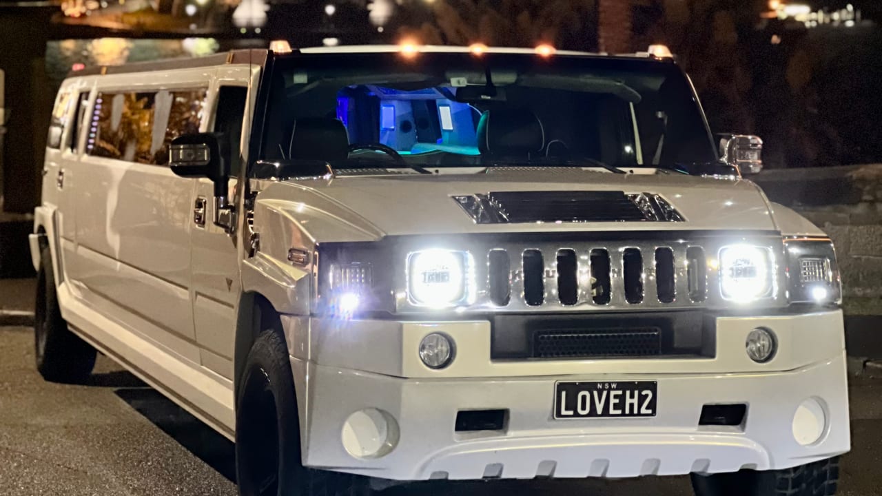White stretch Hummer limousine at night with the Sydney Harbour Bridge behind