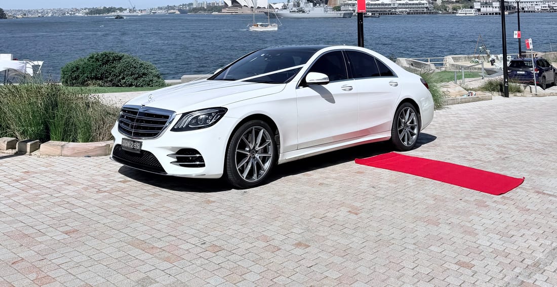 White Mercedes S Class AMG sedan with a red carpet, Sydney Harbour Bridge and Opera House behind